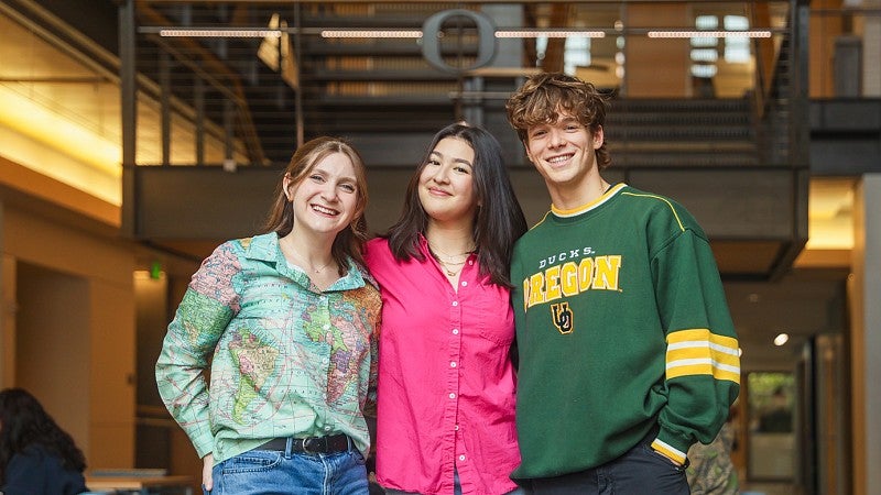 three students pose in front of the Allen Hall staircase