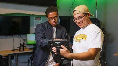 Two SOJC students review an augmented reality experience designed with Snapchat in the SOJC immersive media lab