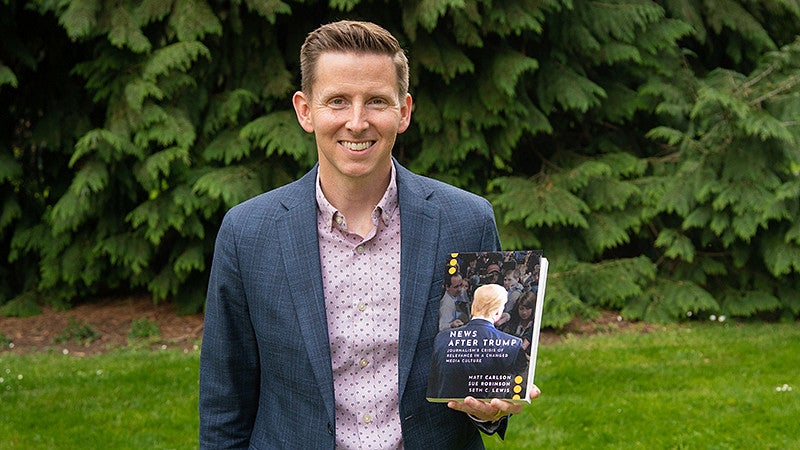 Seth Lewis holds a copy of his book "News After Trump"