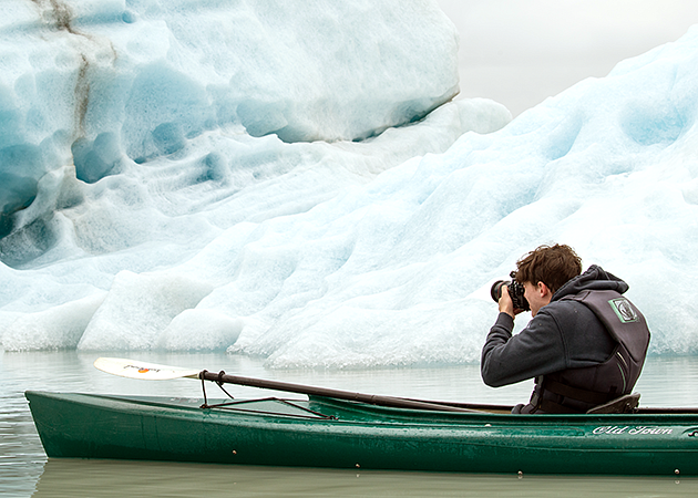 a student in a canoe shoots photos of a glacier