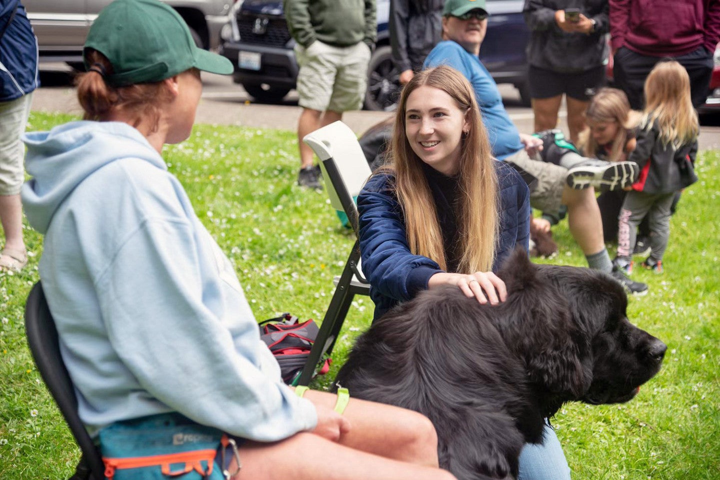 Alexis Weisend pets a large black dog while talking to its owner