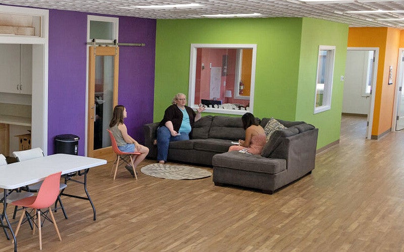three people sit in a brightly colored room during an interview