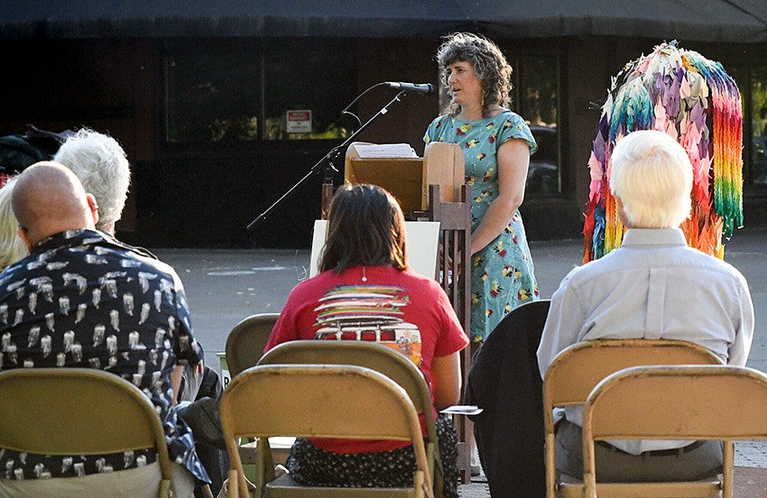 people sit at a news conference while a person speaks at a podium