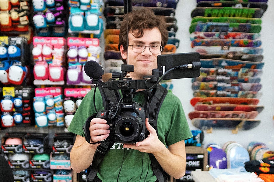 a student in the Story Arc Workshop films with a video camera in a skateboard shop