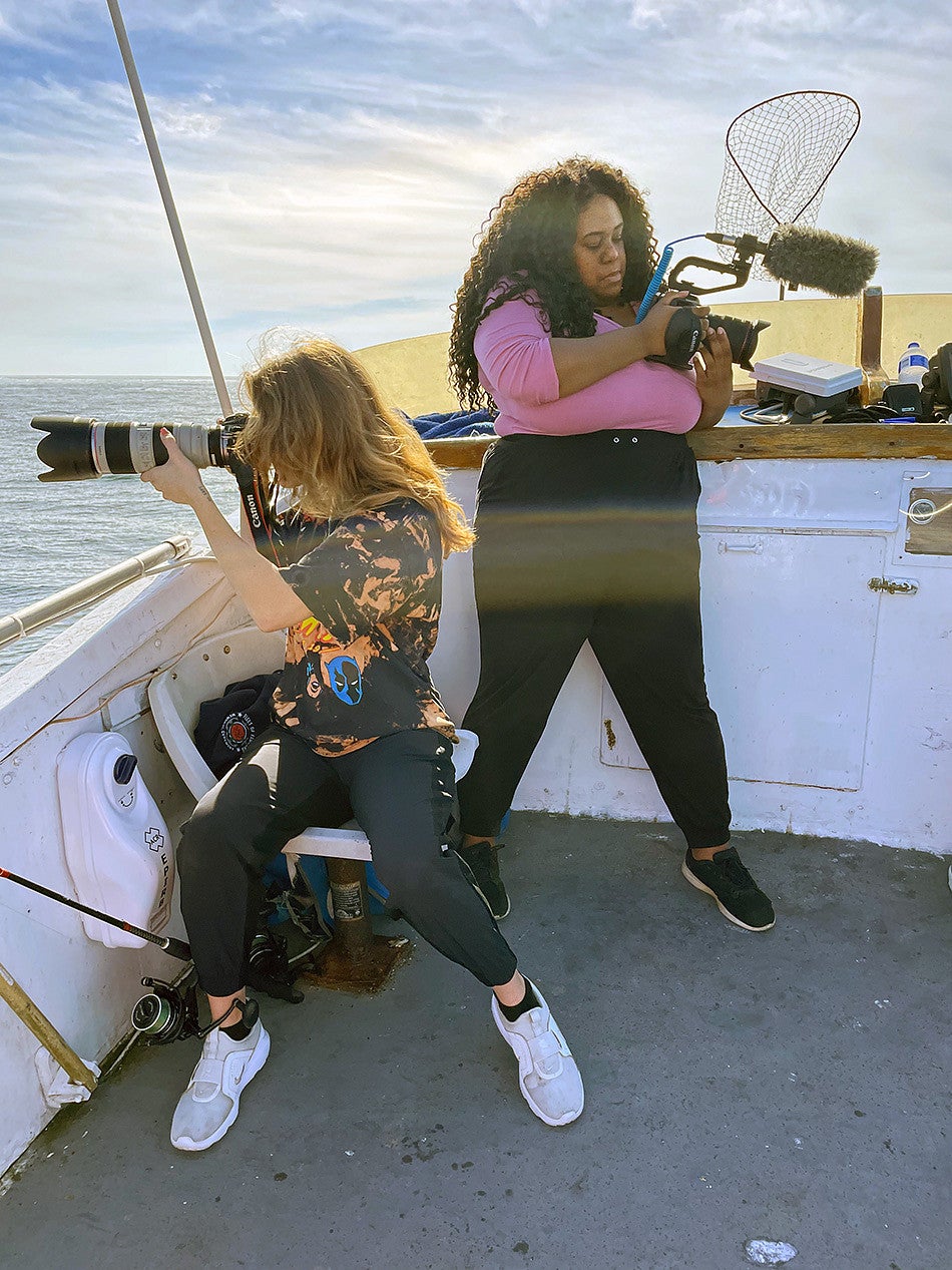 Caitlin Crowley and Ranya Savant use camera equipment on a boat