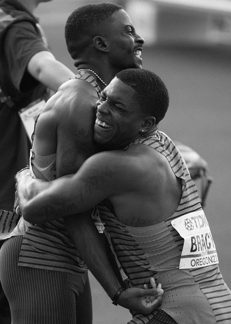 black and white image of two track athletes embracing in joy. Photo by Chloe Montague.