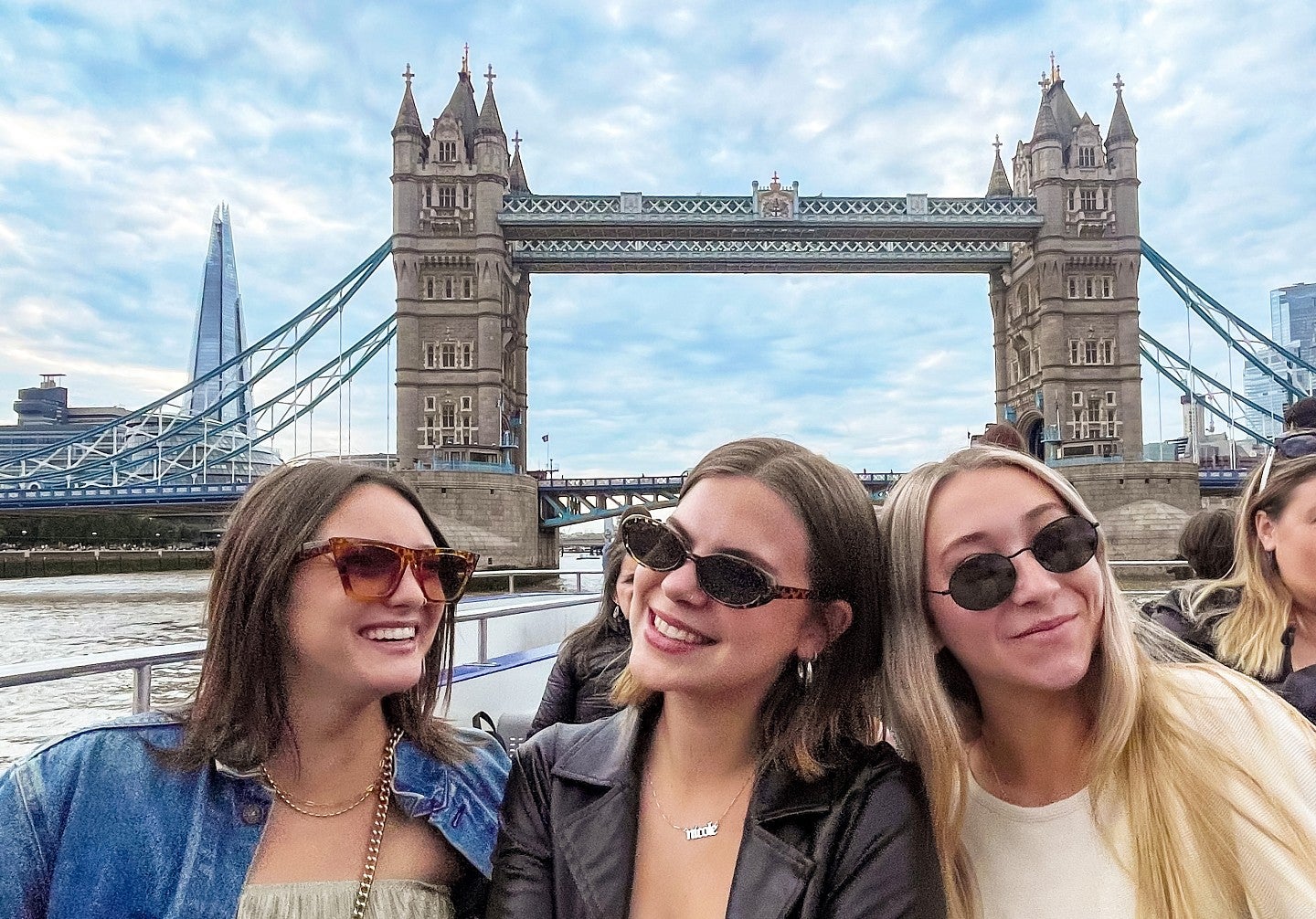 three students pose in front of a bridge in London