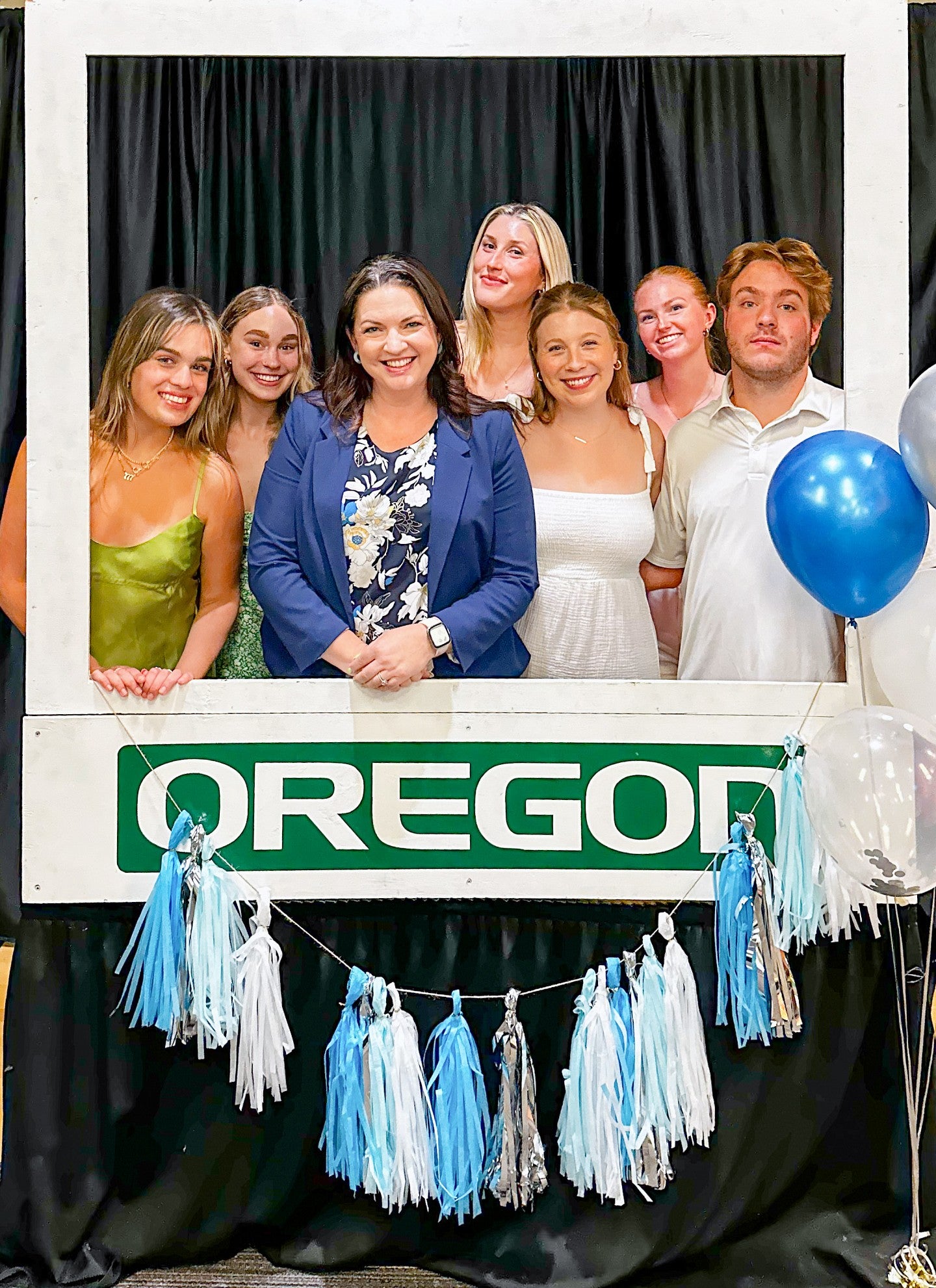 AHPR students and Kelli Matthews pose in a oversized paper frame with balloons