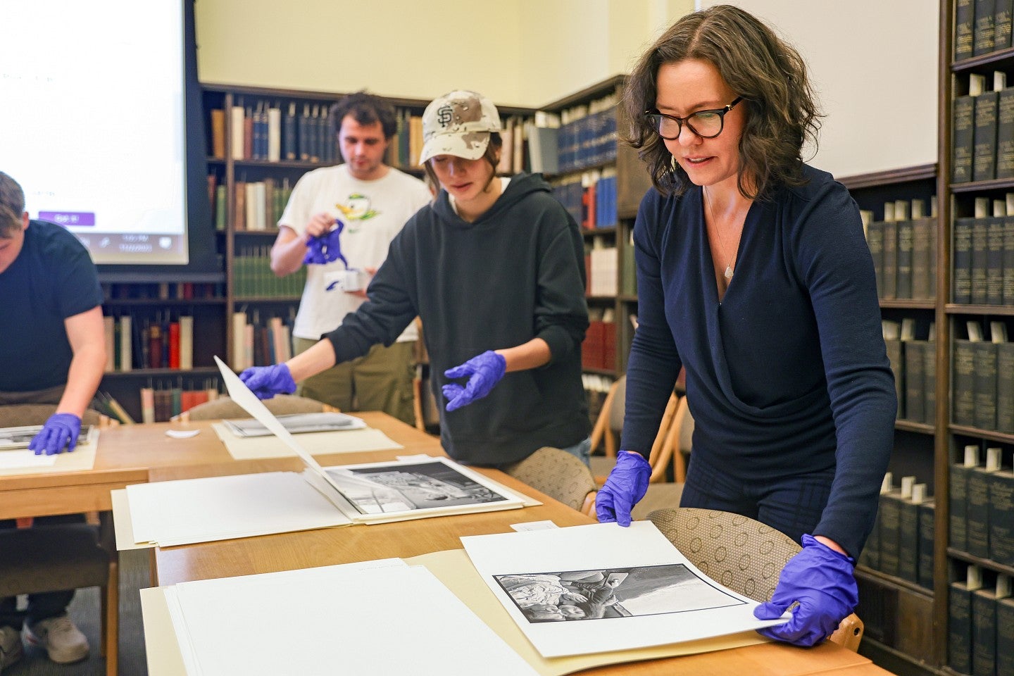 Gretchen Soderlund and students wear purple gloves while handling materials from the UO Libraries' Special Collections