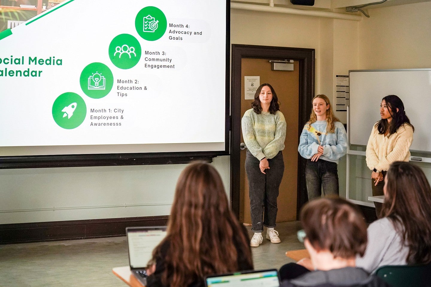 three PR students present a client proposal in front of a projector screen