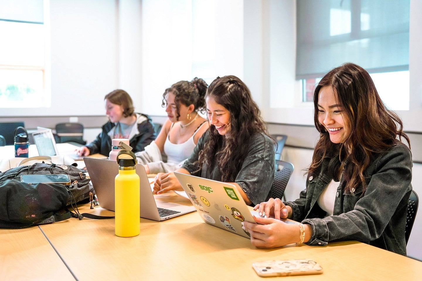 a group of SOJC using laptops at a classroom table