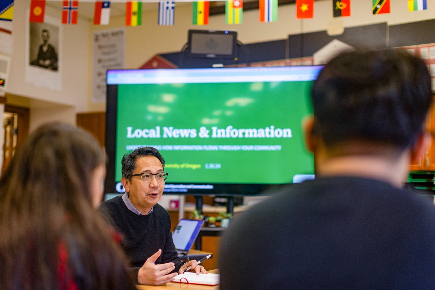 Andrew deVigal, director of the Agora Journalism Center, presents in front of a screen that says "Local News & Information" as he talks to students about community trust in media