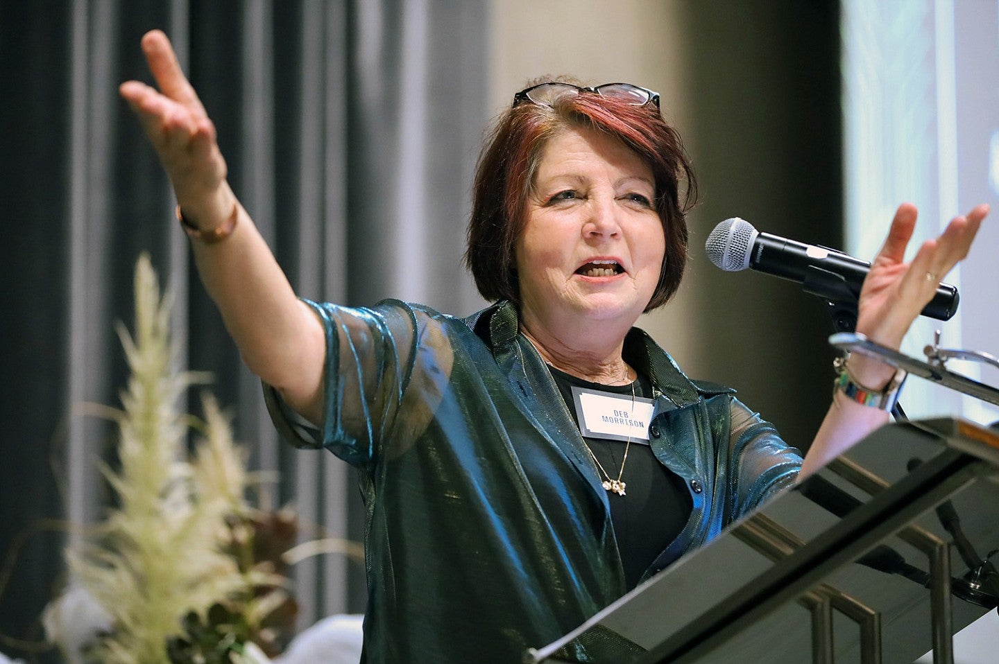 Deb Morrison gestures at a lectern and speaks into a microphone at the SOJC Hall of Achievement gala