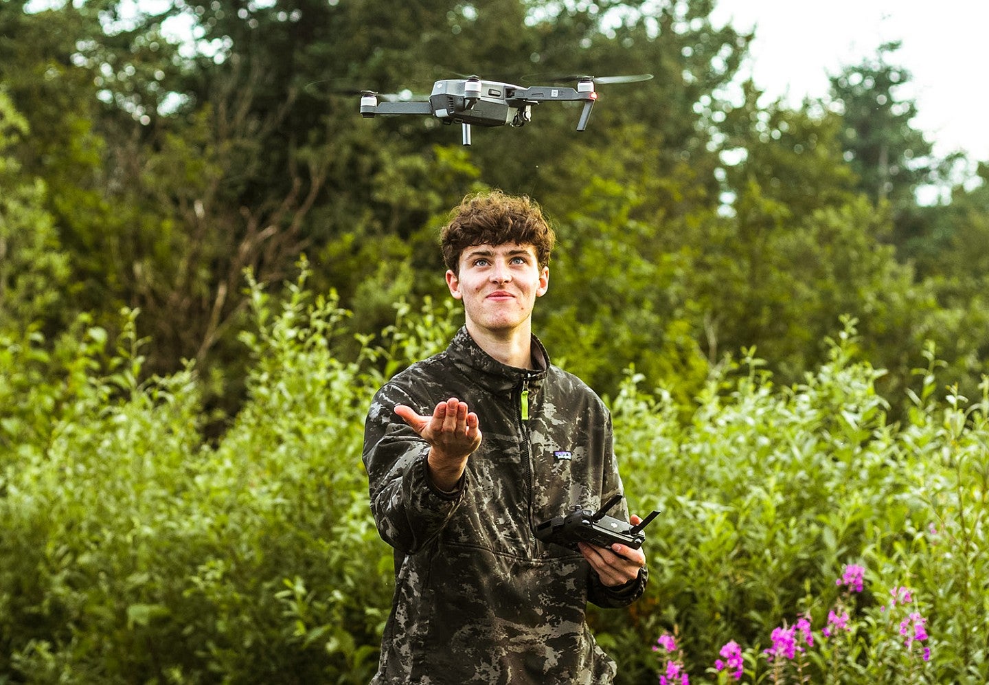 a student stands outside with a drone hovering over their hand