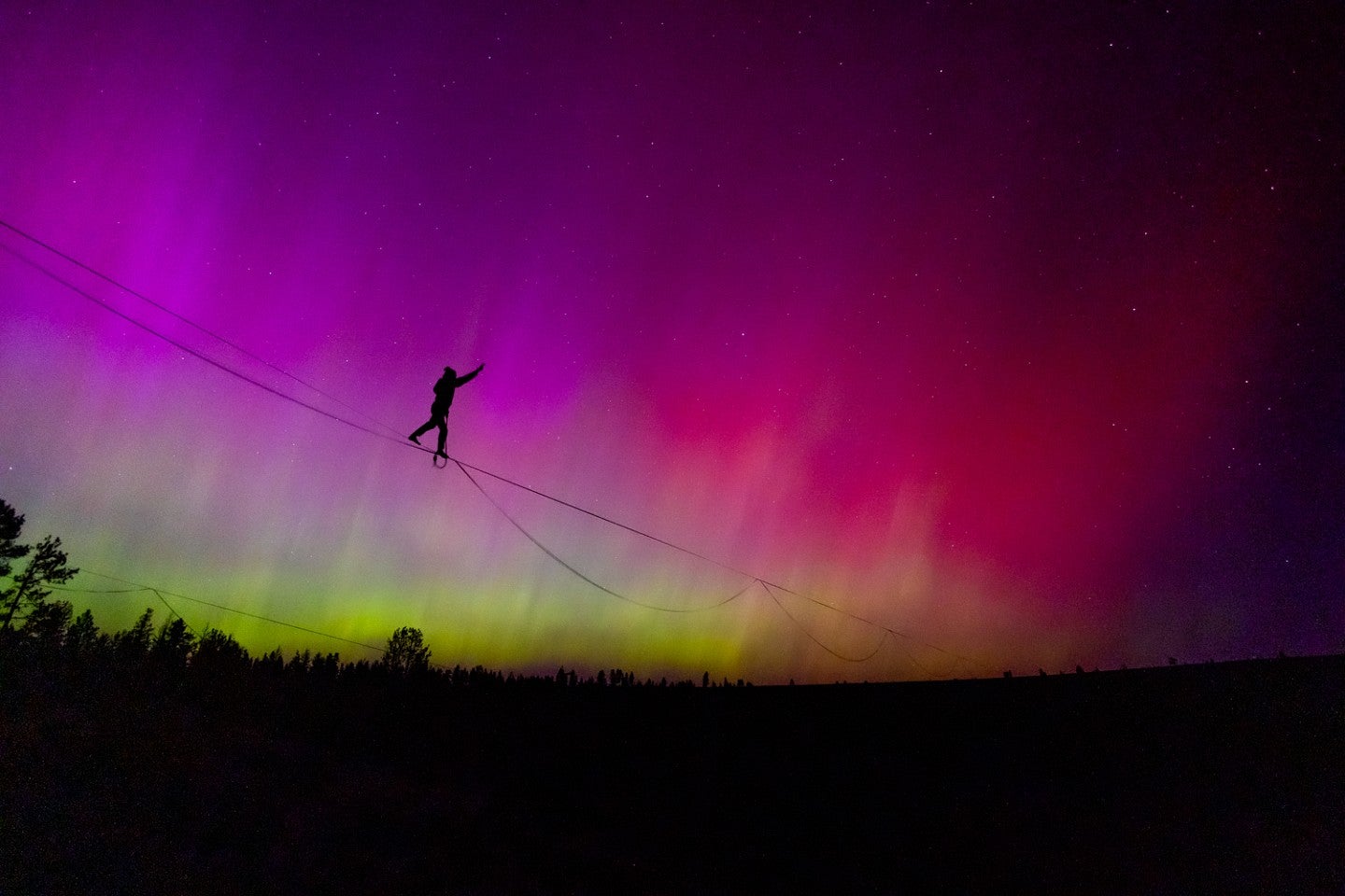 Dan Teitelbaum photo of a person walking on a slackline silhoutted against a brightly colored night sky