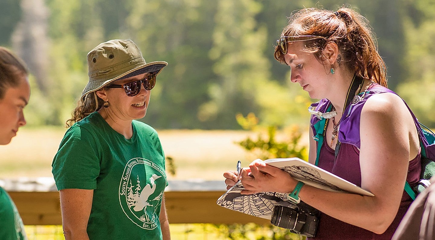 a journalism master's degree student interviews a community member outdoors