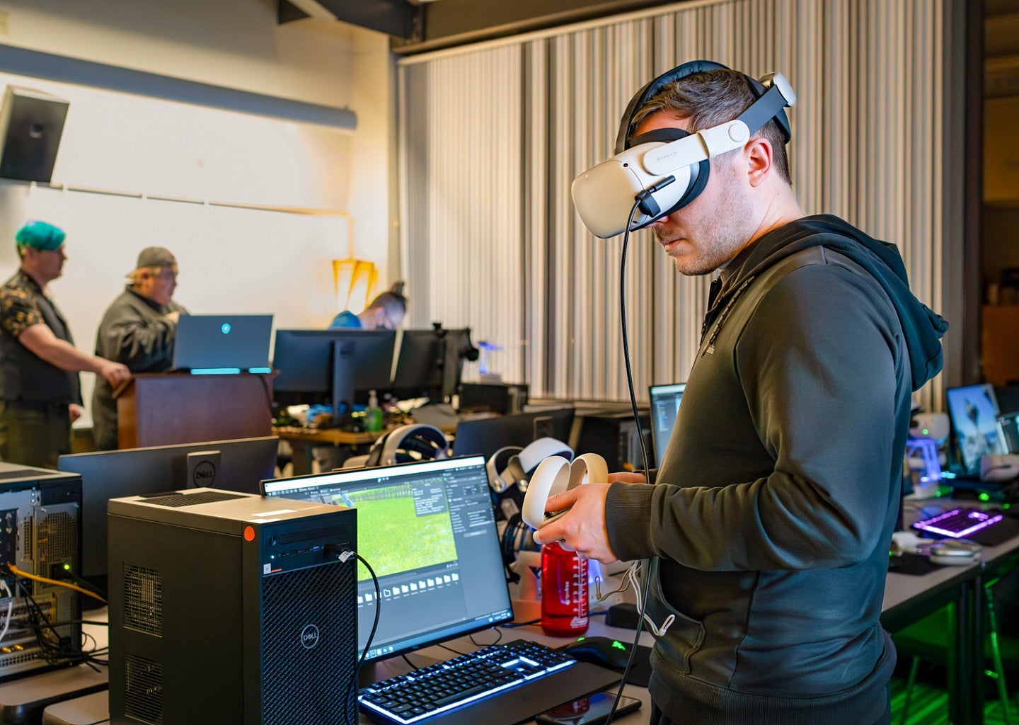 Luke Walker tests an immersive media project on his computer while wearing a VR headset