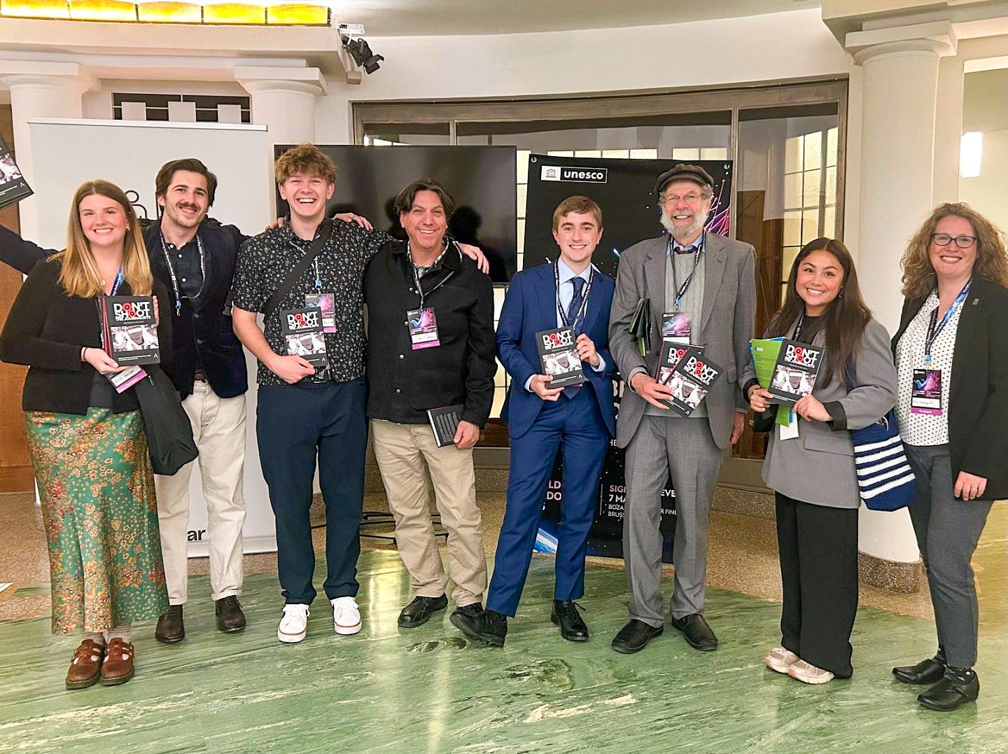 a group of University of Oregon students and professors pose while holding books