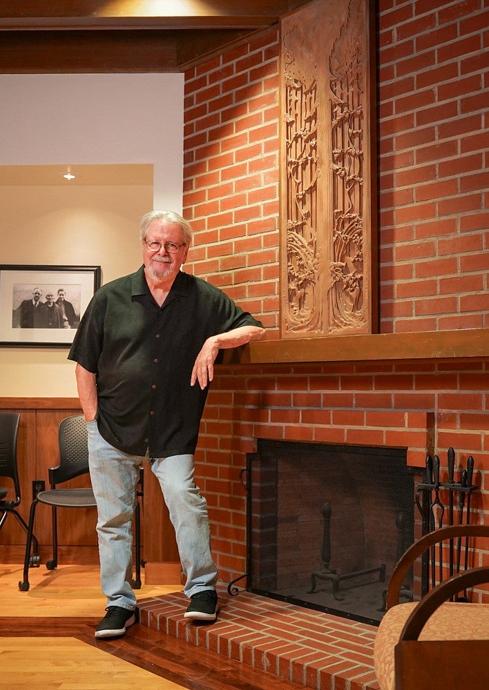 Tom Bivins poses next to the brick fireplace in the Allen Room