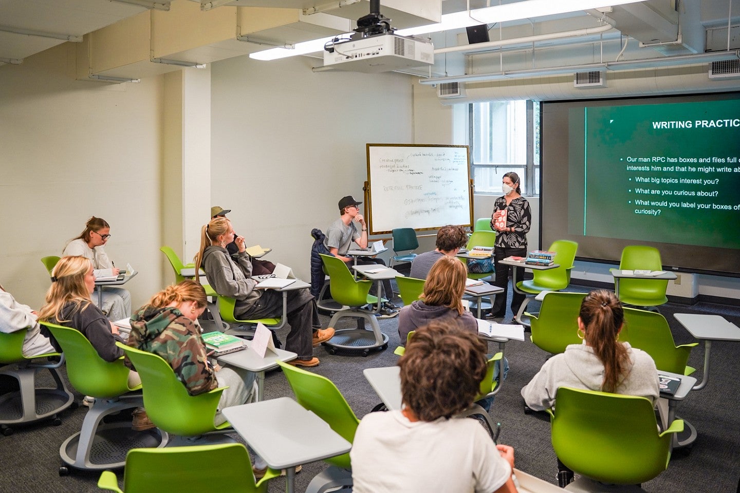 A classroom full of students sitting in bright green chairs facing Lori Shontz