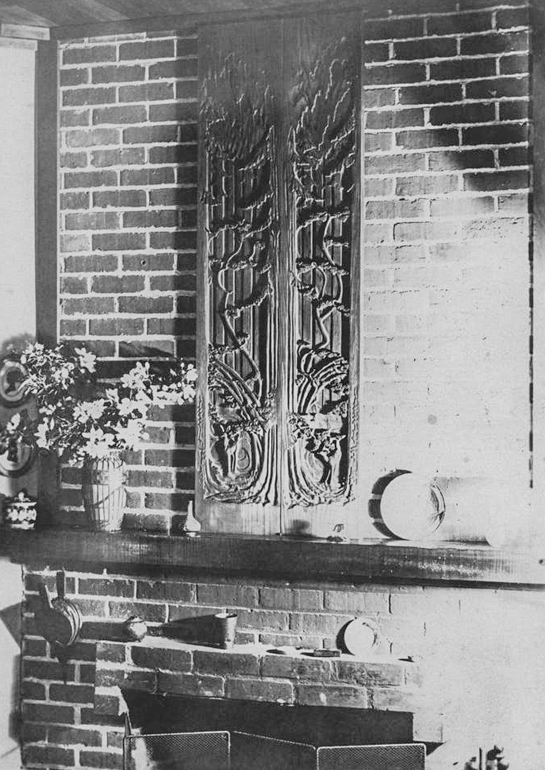 black and white historical photo of Eric W. Allen's home fireplace with a carved wood bas-relief displayed on the mantle