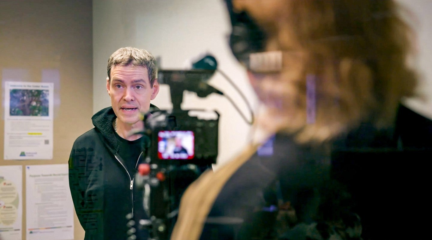 Kelly Clendenon is interviewed on camera with the camera and videographer seen in the foreground