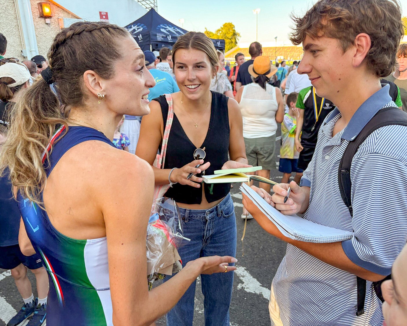 three people talking among a large crowd