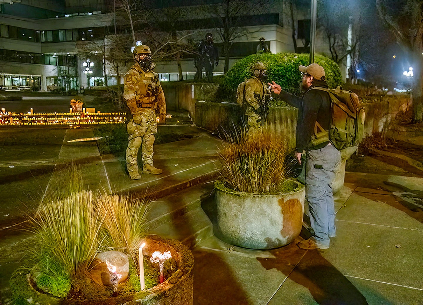 a person speaks to an ICE officer wearing military gear