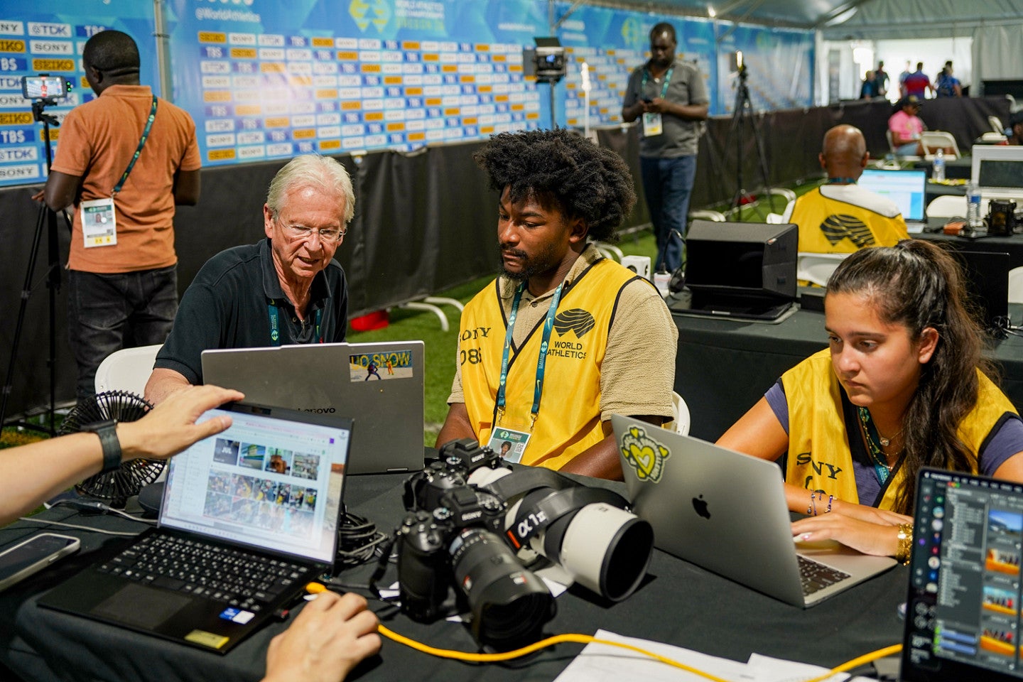 Students edit photos in the press area of a track meet