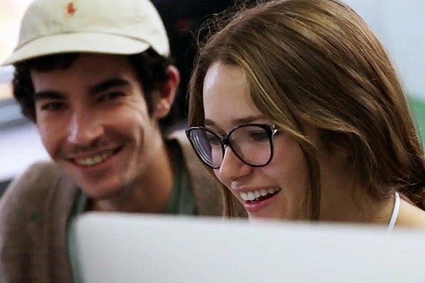 Two students laughing while working at a computer