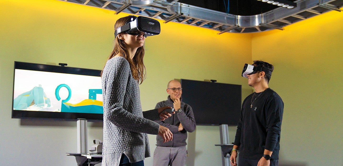 Student wears VR goggles while inside of the immersive media lab. 