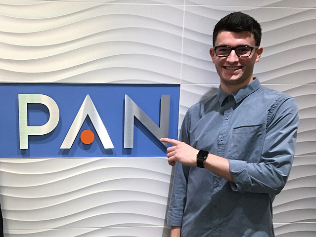 Cameron Rogers standing in front of PAN Communications sign.