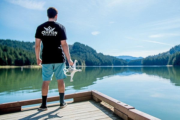 A male student looking out over a lake holding a drone