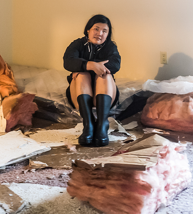 Kezia Setyawan sits among fallen insulation and other debris in her partially demolished apartment after Hurricane Ida