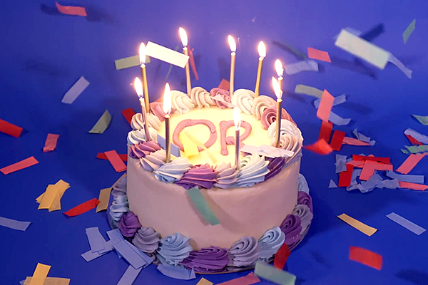 birthday cake with candles and OR written on the top surrounded by confetti