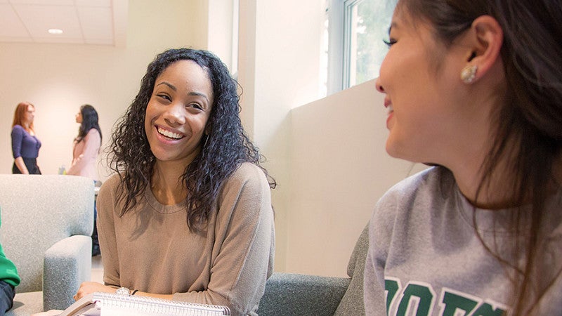 two students sit and laugh while studying