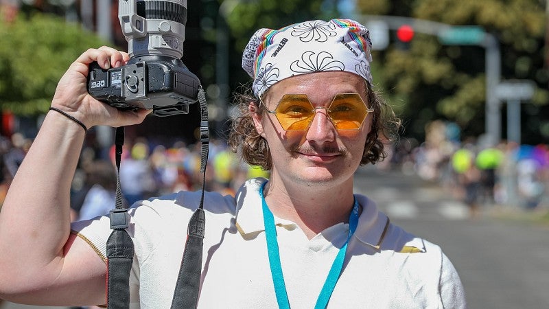 a student journalist holds a camera up at a community parade