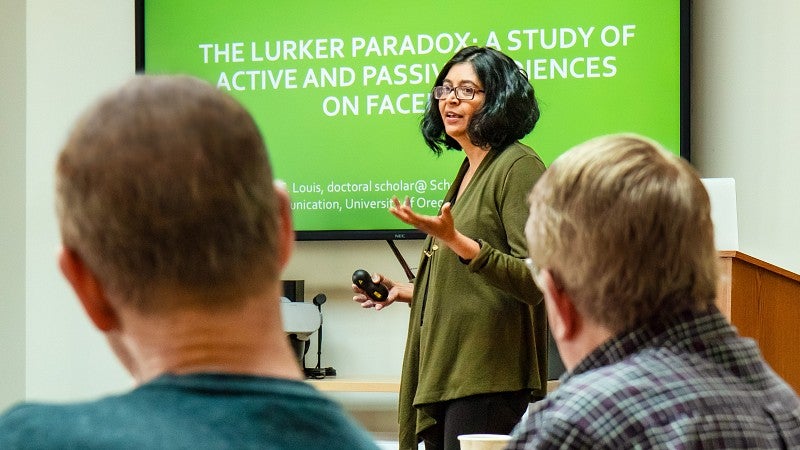 An SOJC doctoral student presents her work in front of a powerpoint screen