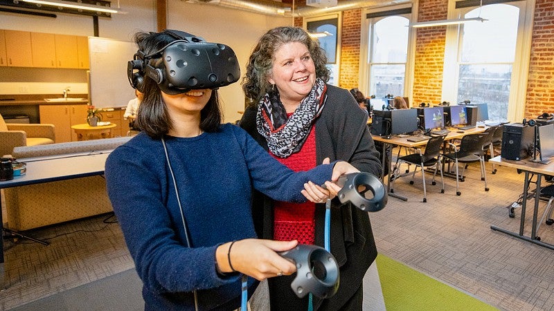 Donna Davis guides a student wearing a VR headset