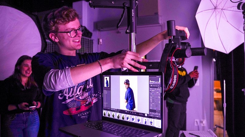 a student adjusts a camera in the Allen Hall studio