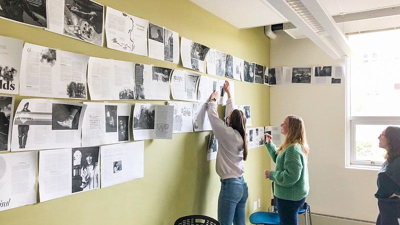 students review printed mockups of FLUX magazine spreads taped to the wall