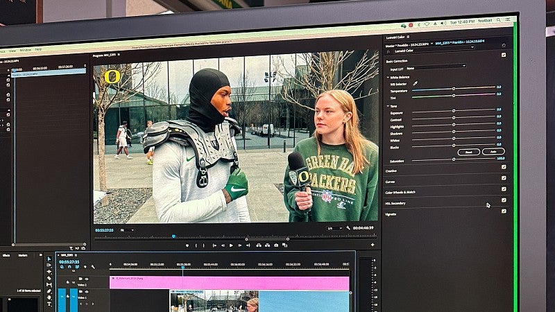 A computer monitor shows a video being edited in Adobe Premiere. The video screenshot shows Sophie Fowler holding a microphone for a student athlete wearing football pads