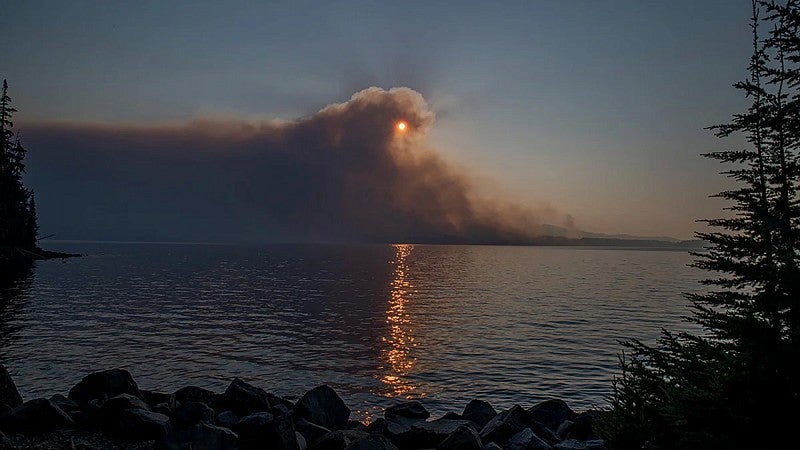 wildfire smoke eclipses the sun over a large body of water