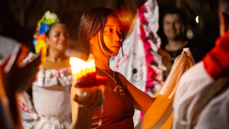 Lizzy Lee holds a candle and dances amid Colombian festival dancers