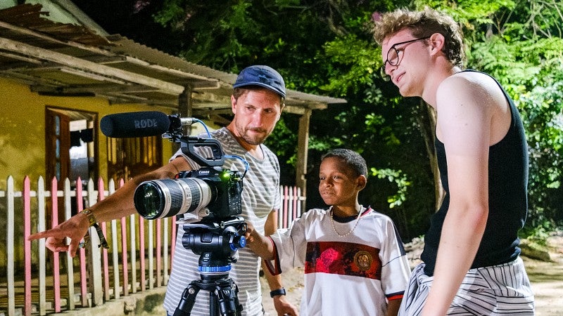 Nick Beccar Varela and Jordan Bentz show a young Colombian boy how to use a video camera