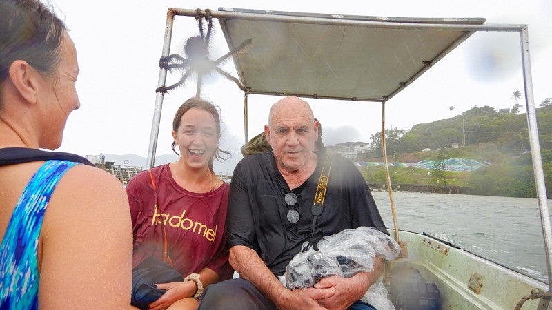 Hollie Smith, Bea Mira, and Dan Morrison smile while on board a small boat on the ocean