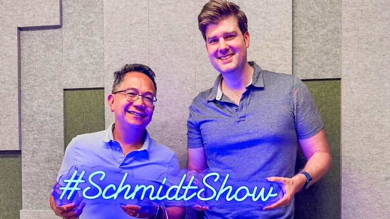 Andrew deVigal and Mike Schmidt pose with a neon sign that says "#SchmidtShow"