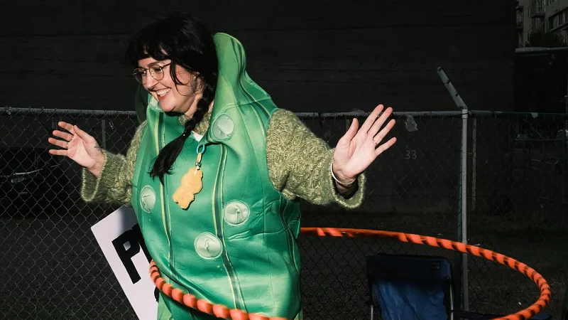 A person attending a peaceful protest in Portland wears a green pickle costume while hula-hooping