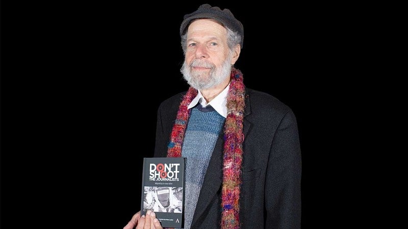 Peter Laufer poses with book title 