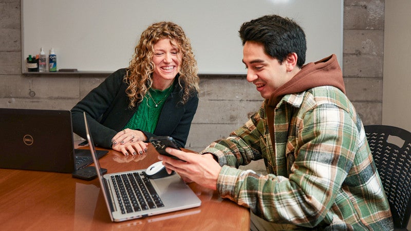 Jessika Kaiser and Adrian Garcia Dena sit at a table with laptops